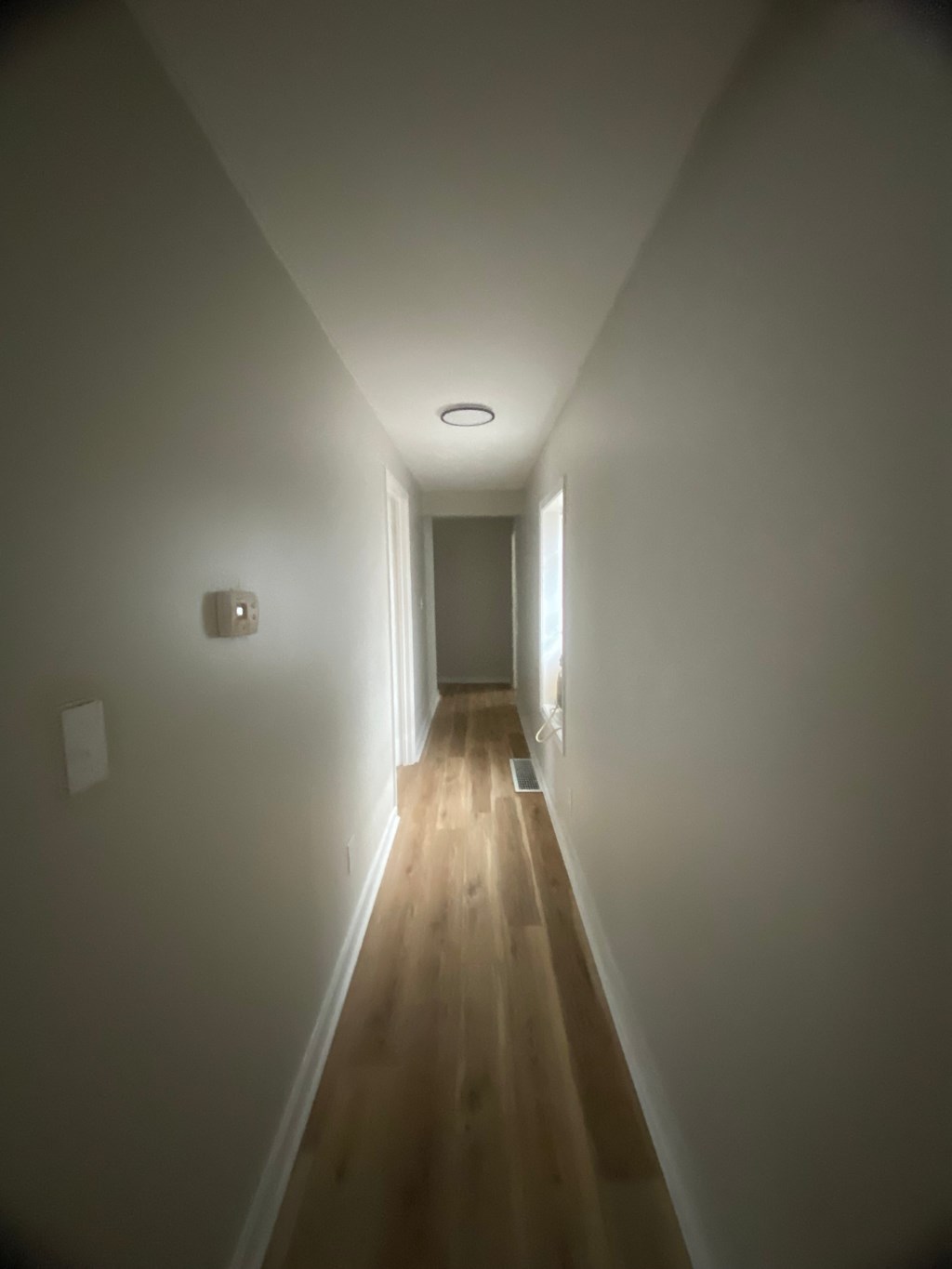 a long hallway with wood floors and white walls