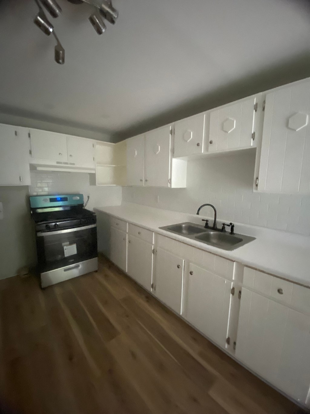 an empty kitchen with white cabinets and a sink