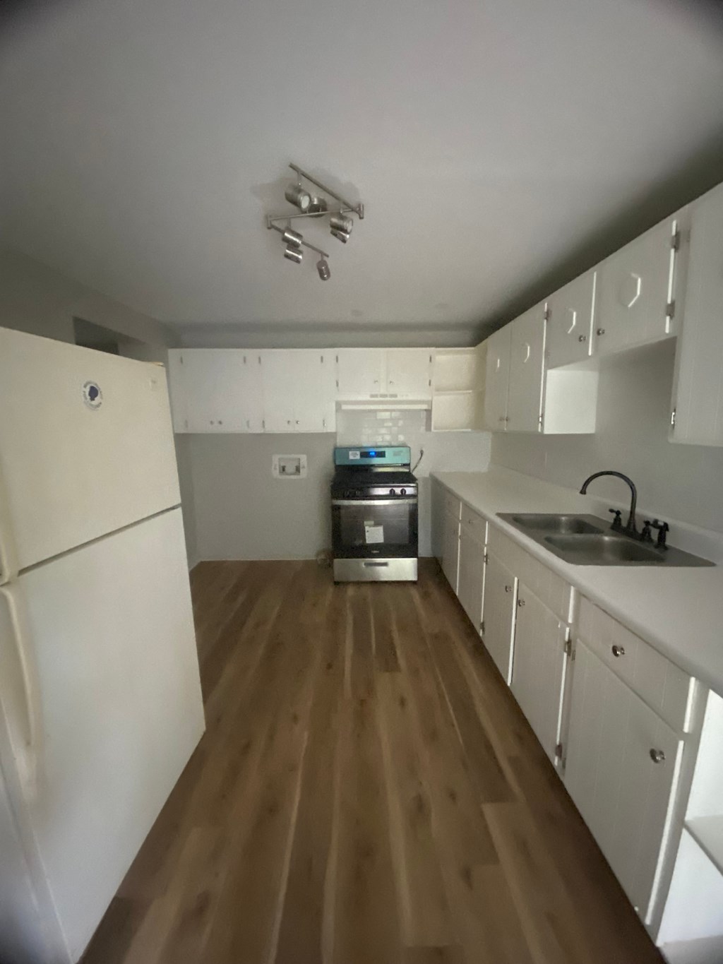 an empty kitchen with white cabinets and a sink