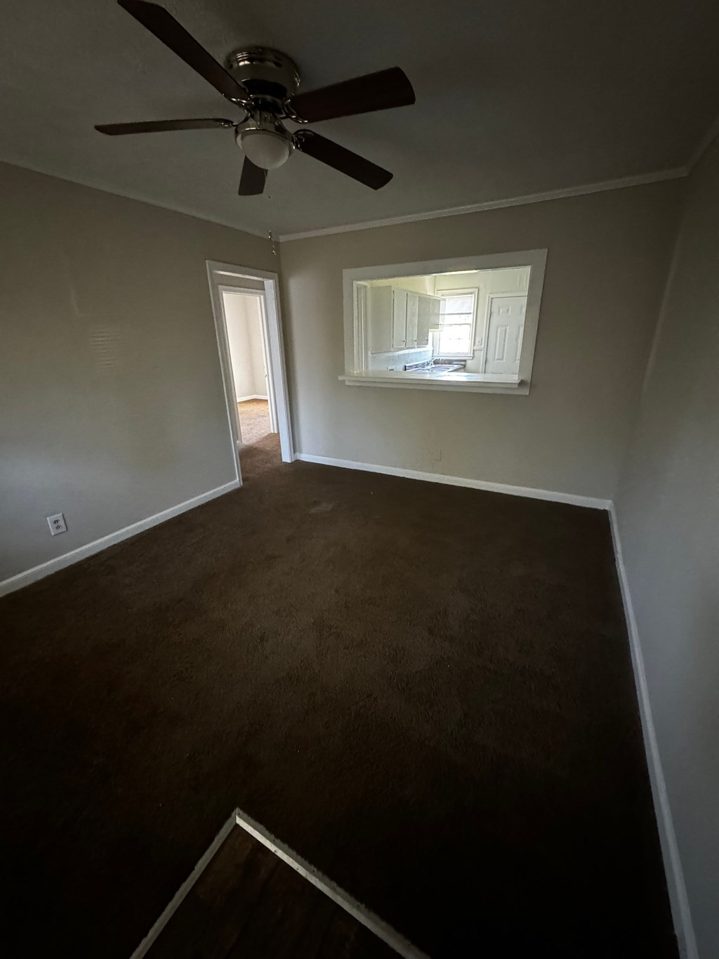 an empty room with a ceiling fan and a window