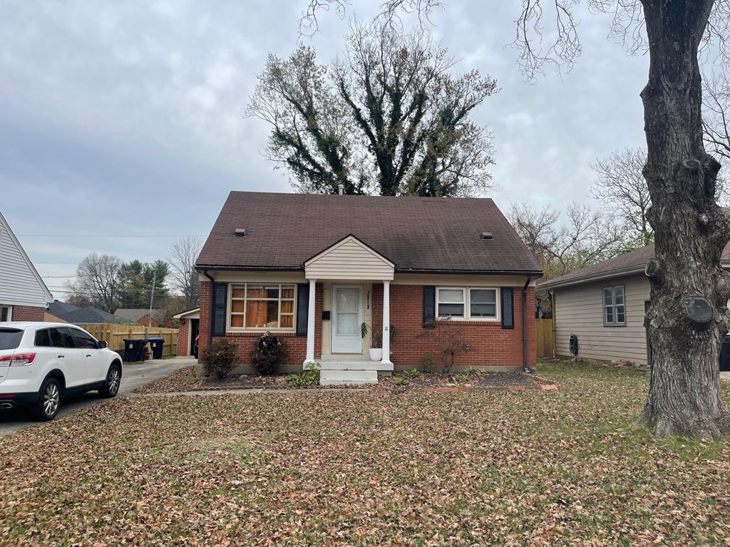 a small brick house with a tree in front of it