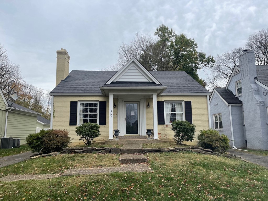 a yellow house with black shutters and a front yard