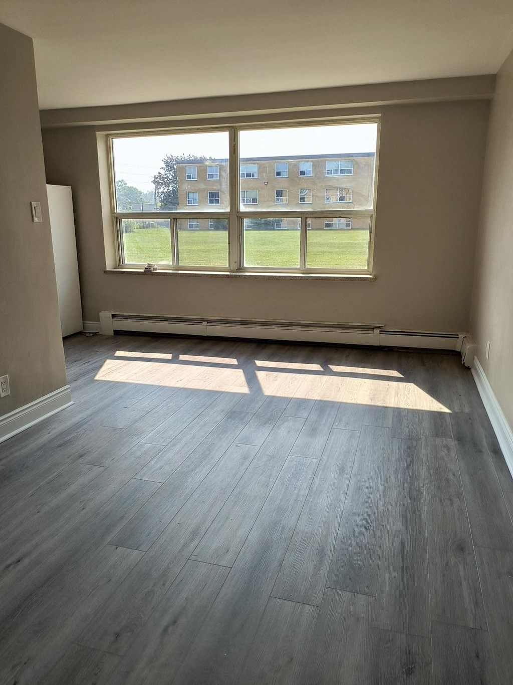 A room with a large window and wooden flooring.