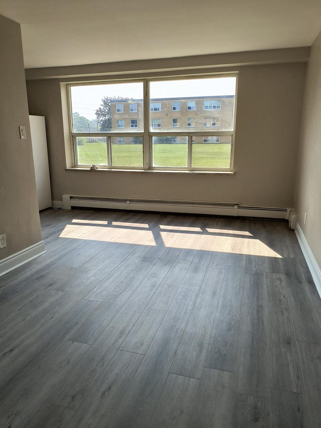 A room with a large window and wooden flooring.