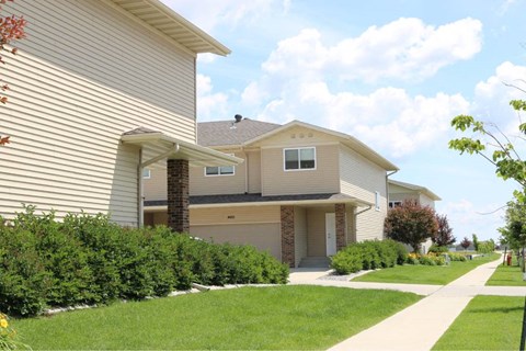 A beige house with a brown door and a small porch.