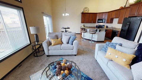 A living room with a grey couch, a coffee table, and a kitchen in the background.