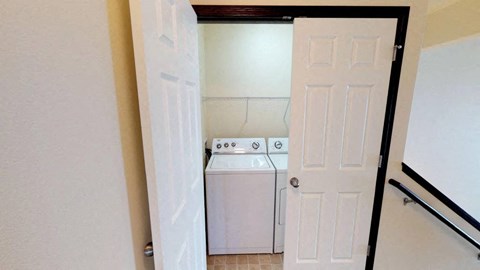 A white washing machine is in a small laundry room.