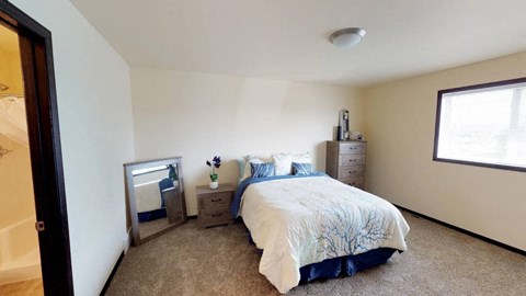 A bedroom with a bed, nightstand, and a window.