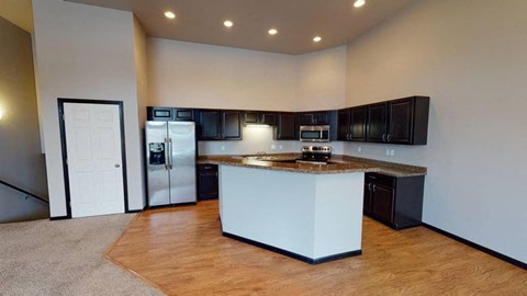 A kitchen with a white island and black cabinets.