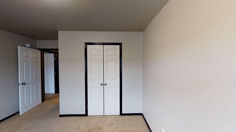 A room with a white door and carpeted floor.