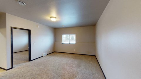 A room with a window and a carpeted floor.