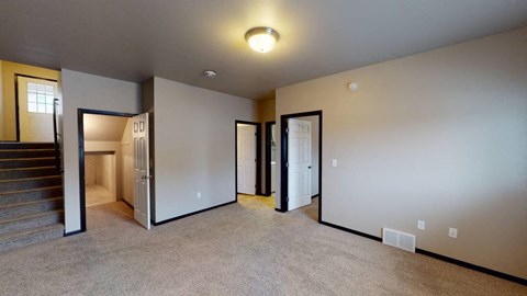 A room with a staircase and three doors.