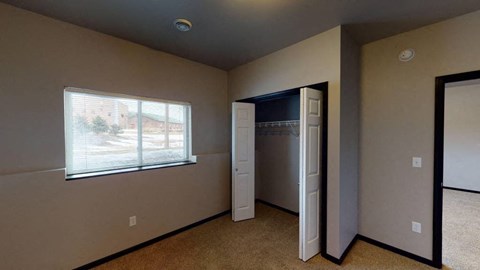 A room with a window, a door, and a wall-mounted refrigerator.
