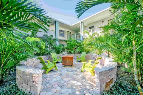 A patio with a table surrounded by green plants.