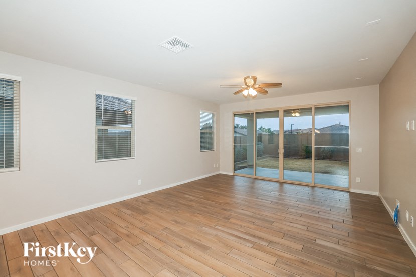 A spacious room with wooden floors and a ceiling fan.