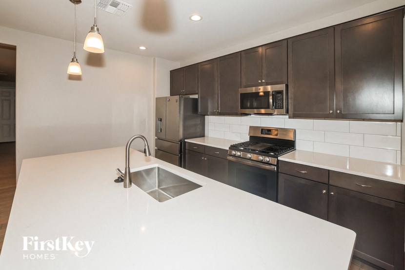 A modern kitchen with a white countertop and dark brown cabinets.