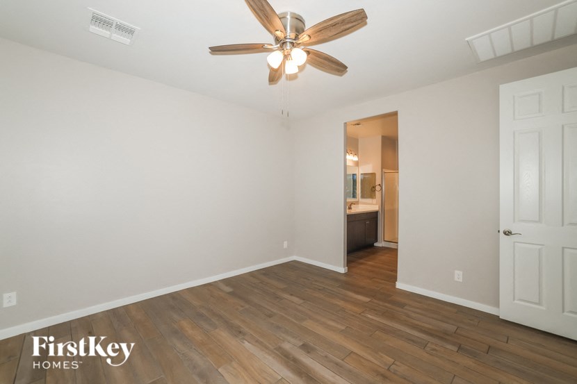 A room with a ceiling fan and wooden flooring.