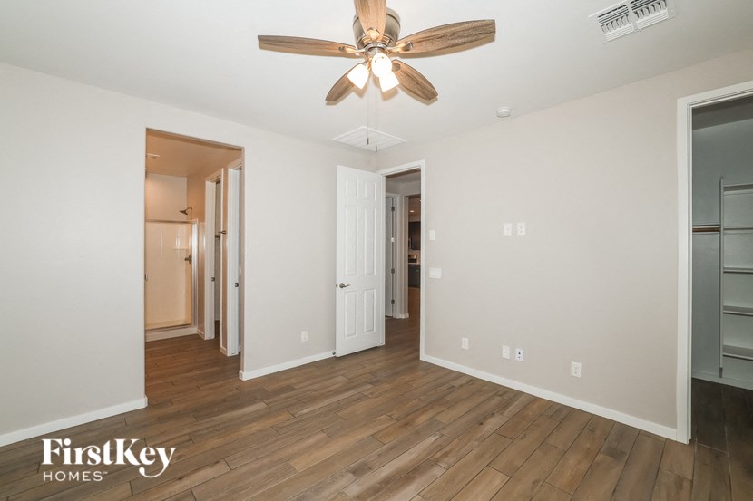 A room with a ceiling fan and wooden floors.