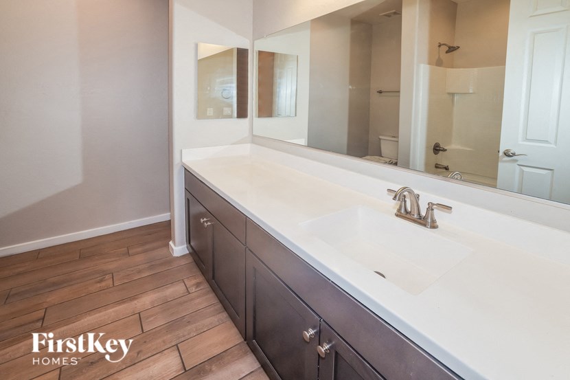 A bathroom with a wooden floor and a white sink.