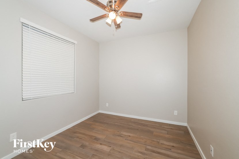 A room with a ceiling fan and wooden flooring.