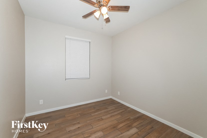 A room with a ceiling fan and wooden flooring.