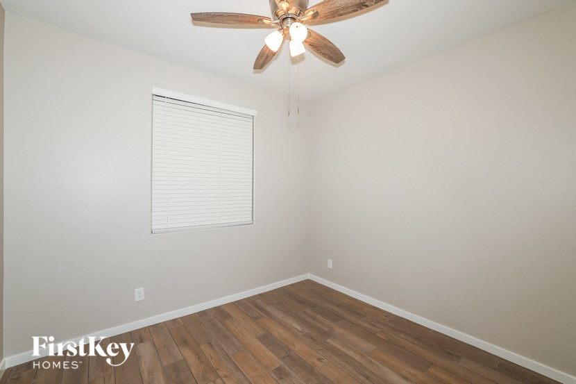 A room with a ceiling fan and wooden flooring.