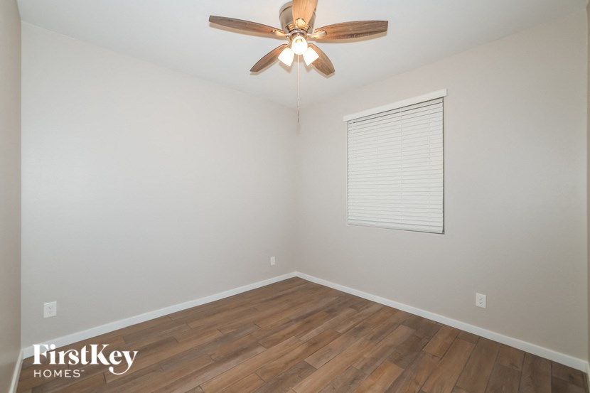 A room with a ceiling fan and wooden flooring.