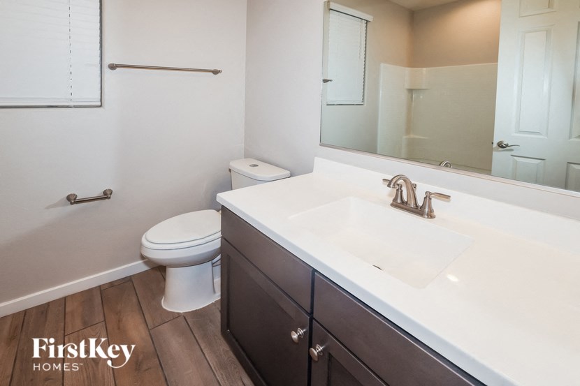 A bathroom with a toilet, sink and mirror.
