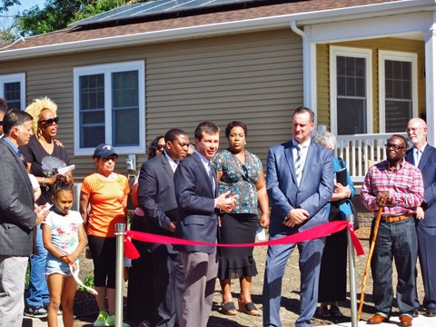 A ribbon cutting ceremony outside a house.