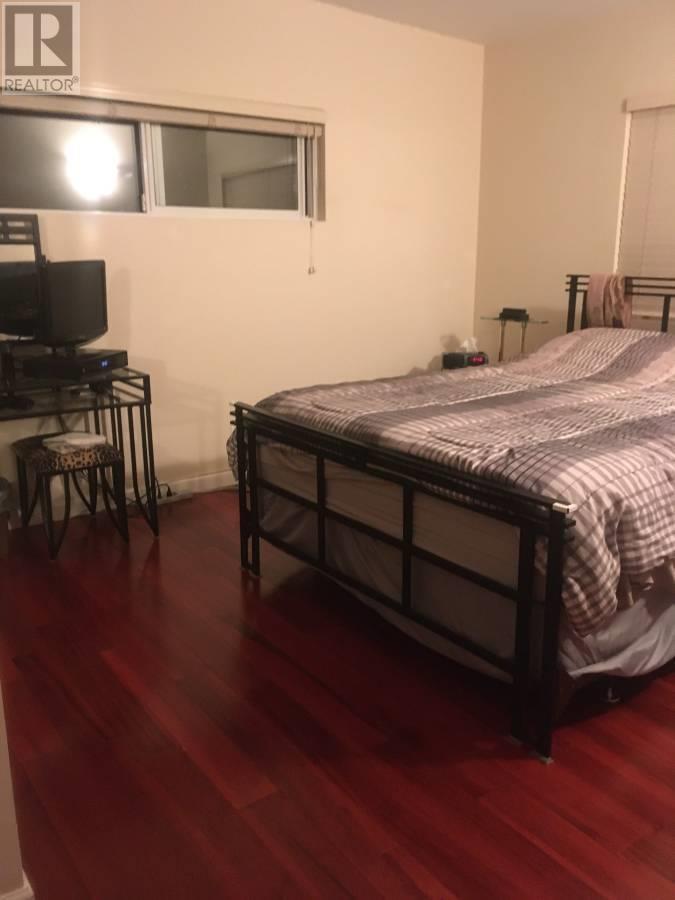 A bedroom with a bed, chair, and television.