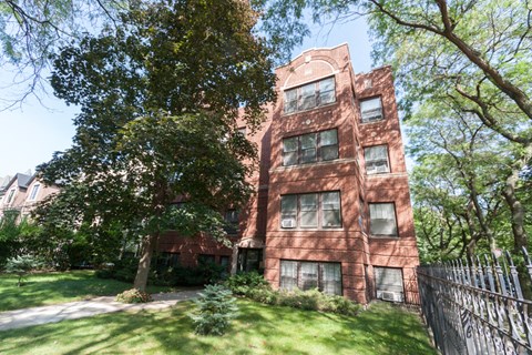 an old brick building with grass and trees in front of it