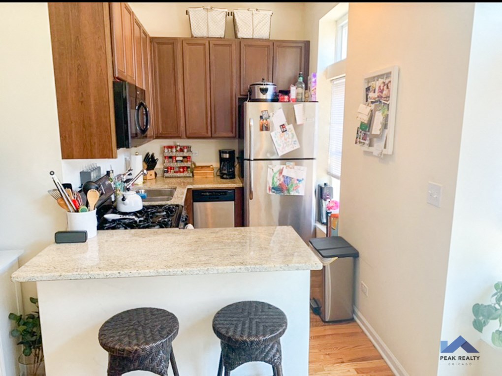 a kitchen with a counter and stools in front of a refrigerator