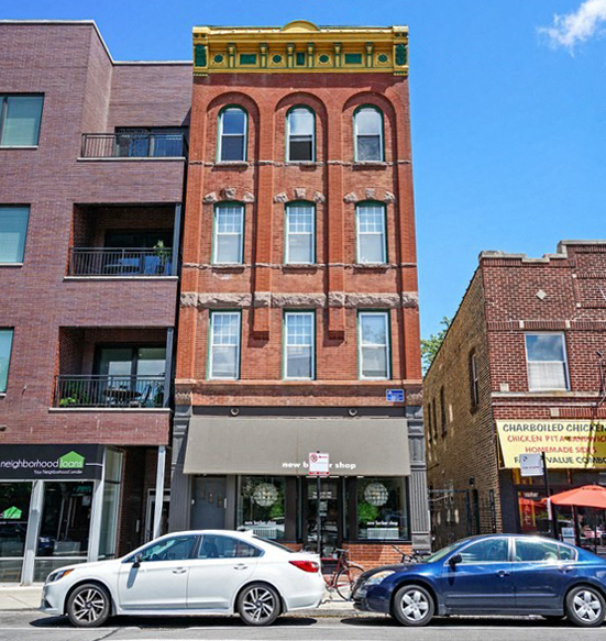 a tall brick building with two cars parked in front of it