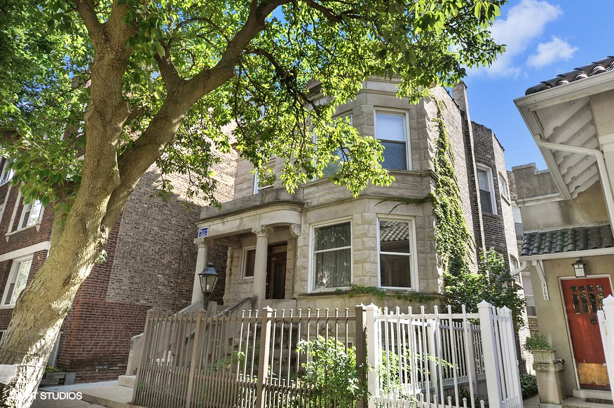 a house with a fence and a tree in front of it