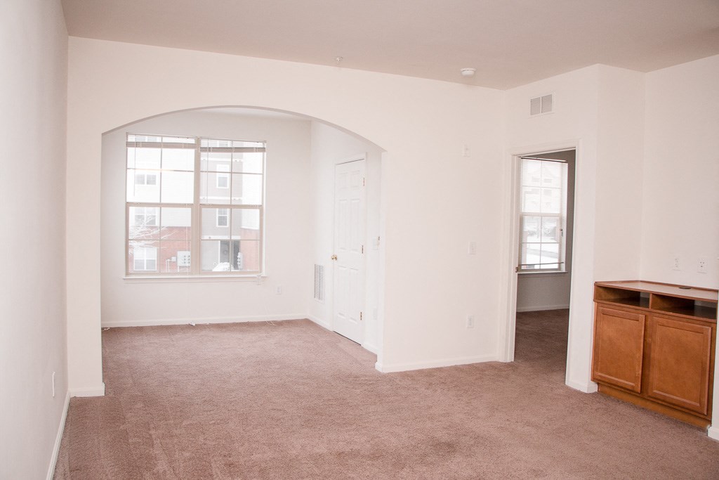 an empty living room with a window and a dresser