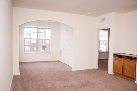 an empty living room with a window and a dresser