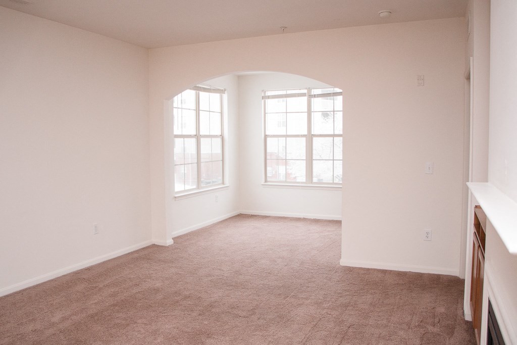 an empty living room with a large window and carpet
