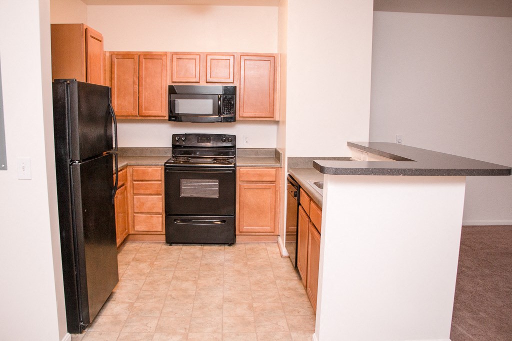 a kitchen with wooden cabinets and a black stove and refrigerator