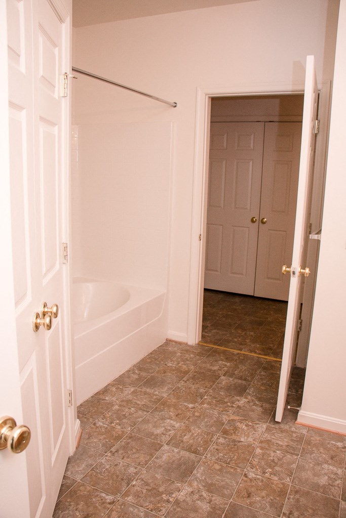 a bathroom with a tub and a door and a closet