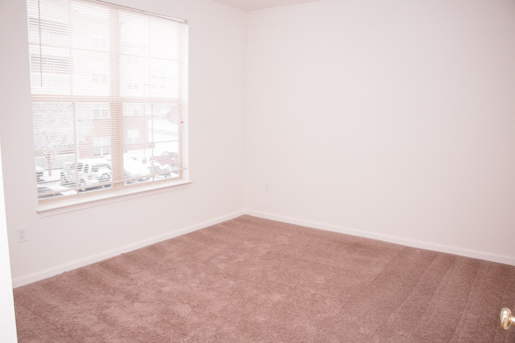 an empty room with a window and a carpet