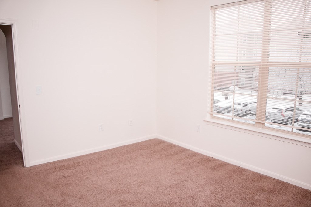 an empty room with a window and a carpet