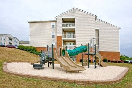 a childrens playground with a slide in front of an apartment building