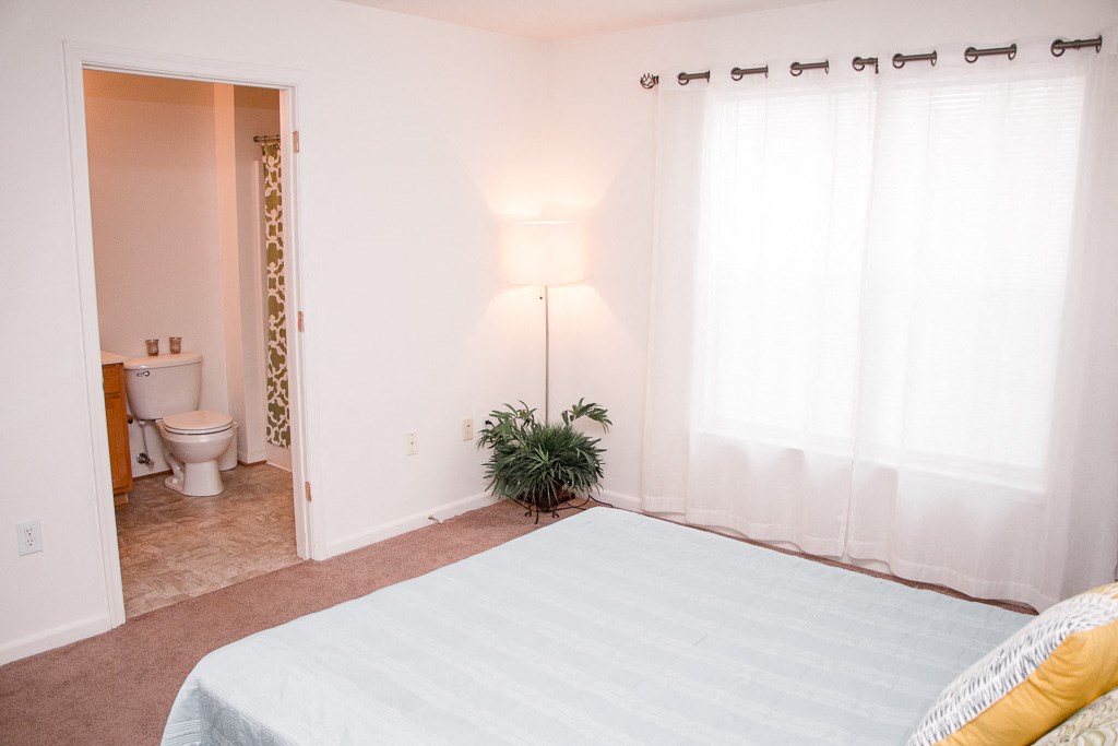 a bedroom with a bed and a bathroom with a toilet