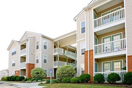 a row of apartment buildings with balconies and a yard