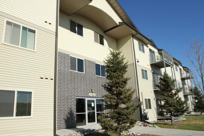 an apartment building with a tree in front of it