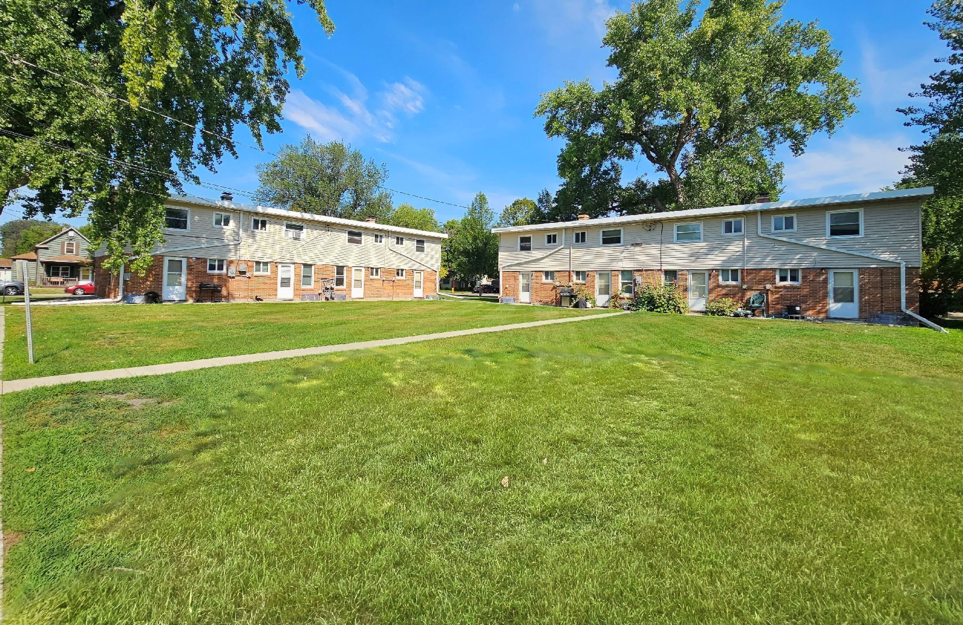 a green lawn in front of two apartment buildings