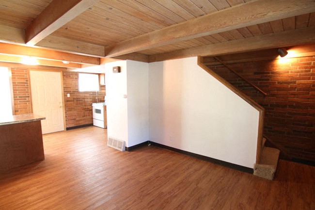 an empty living room with a white wall and wood floors