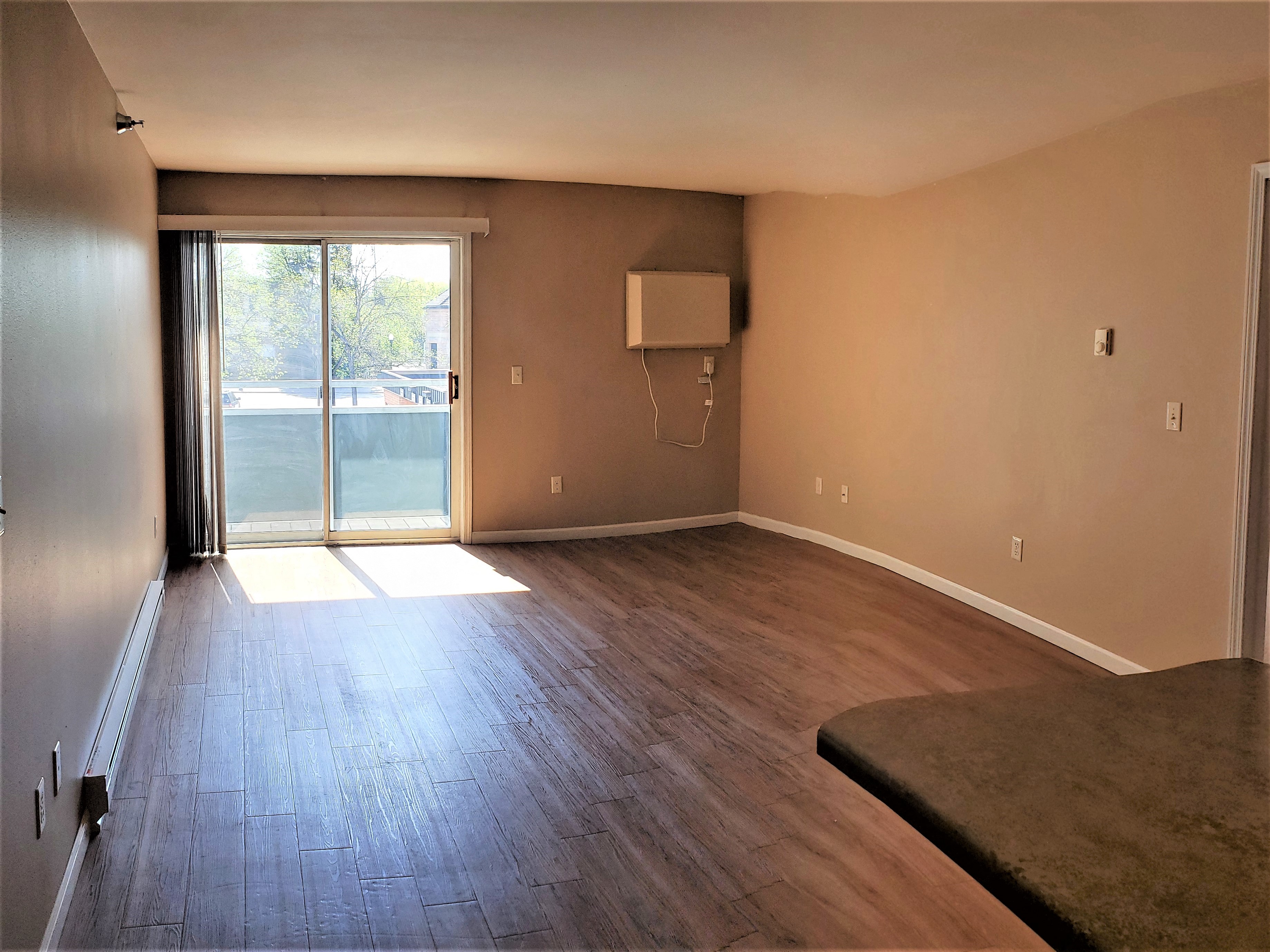 an empty living room with wood floors and a sliding glass door