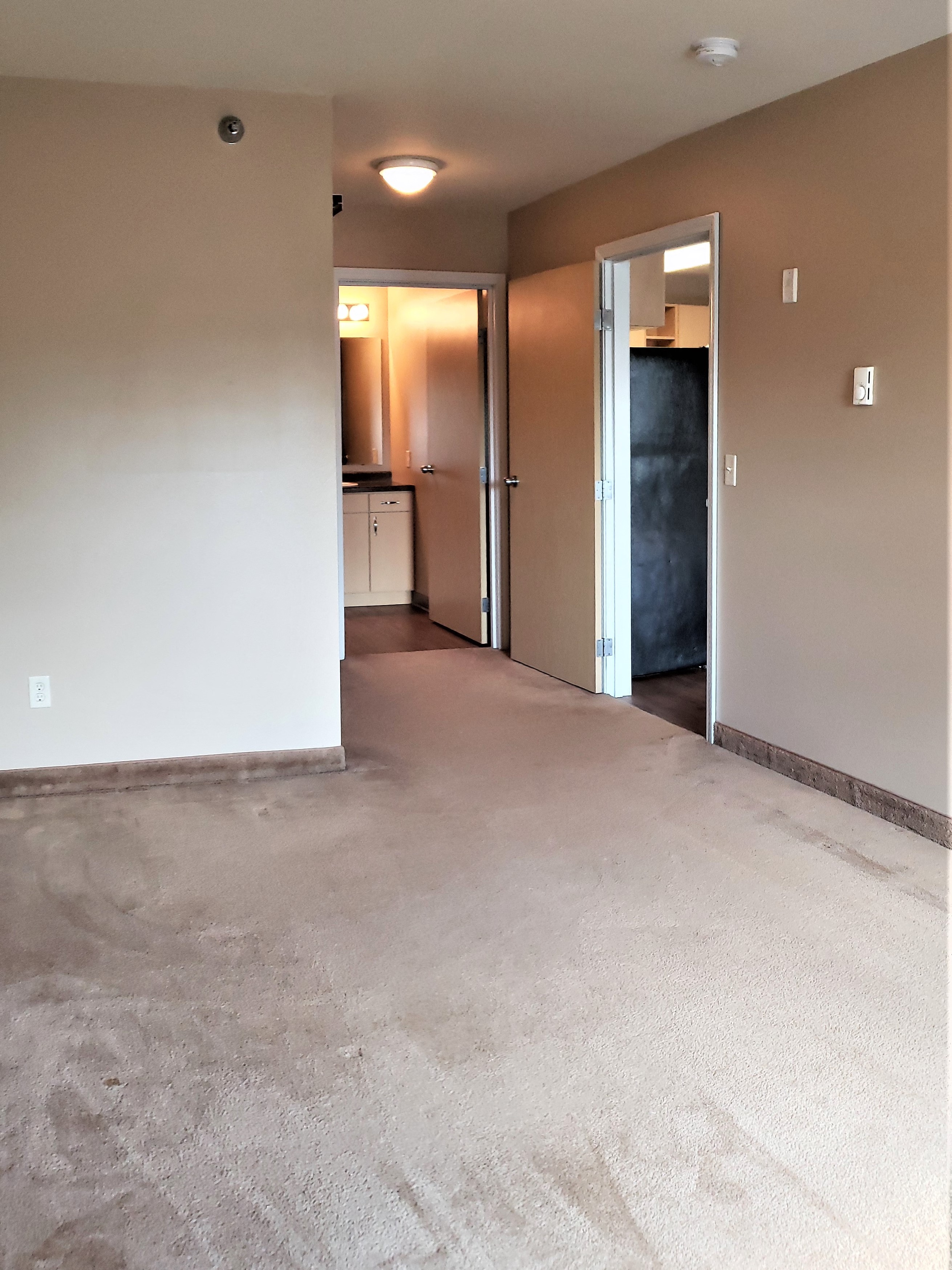 the living room and kitchen of an empty house with a carpeted floor