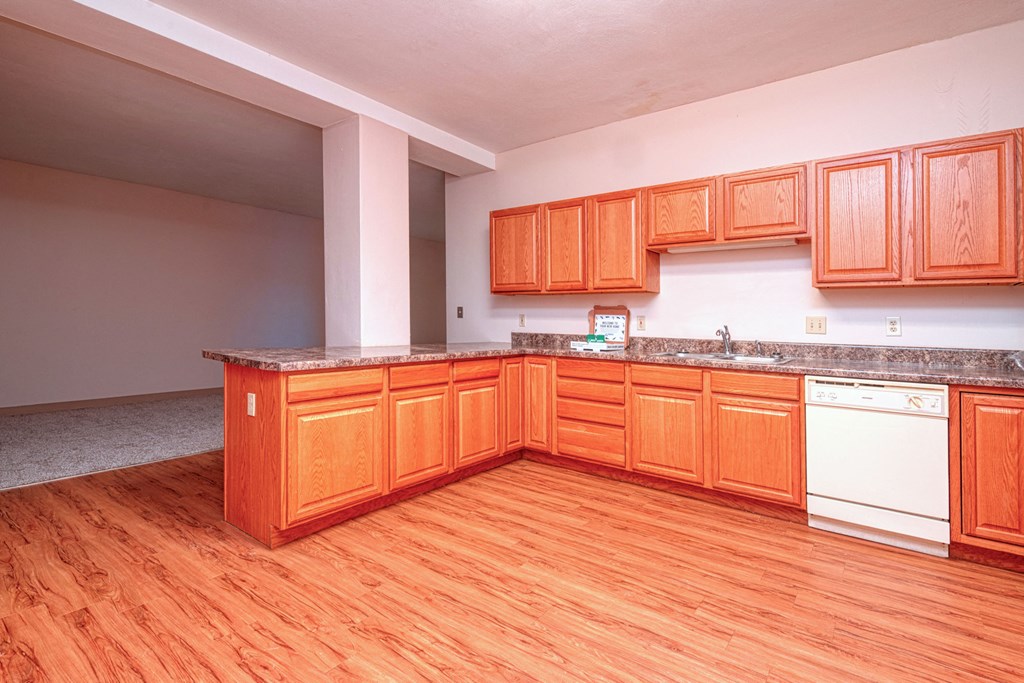 an empty kitchen with wood flooring and wooden cabinets